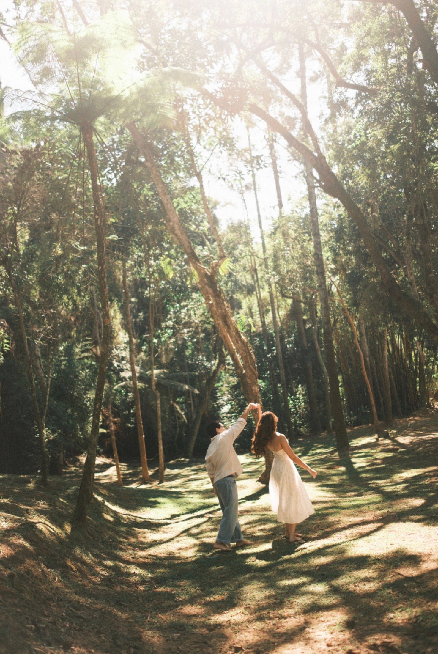 Casal dançando no bosque com luz natural